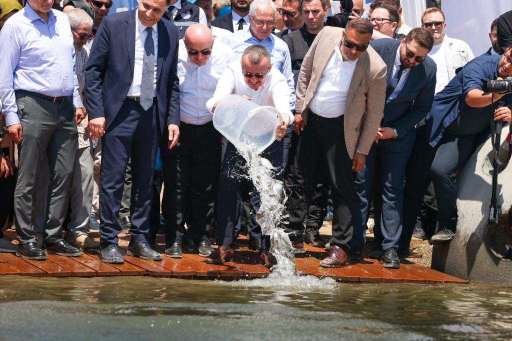 Bir grup insan, su dolu bir kabı suya dökerken görüntülenmiş.